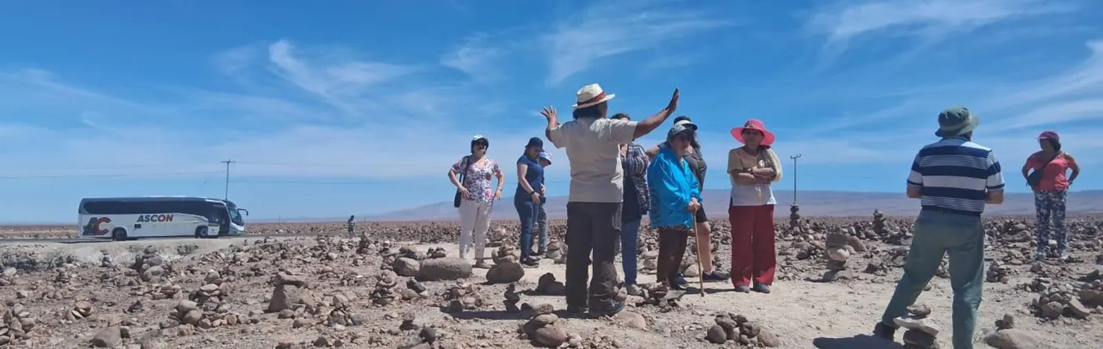Grupo de turistas con guía en el altiplano, bus ASCON al fondo