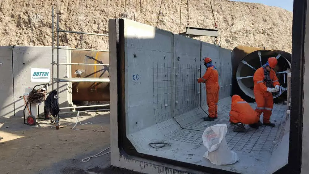 Operarios con traje naranjo instalando un módulo prefabricado en un túnel minero